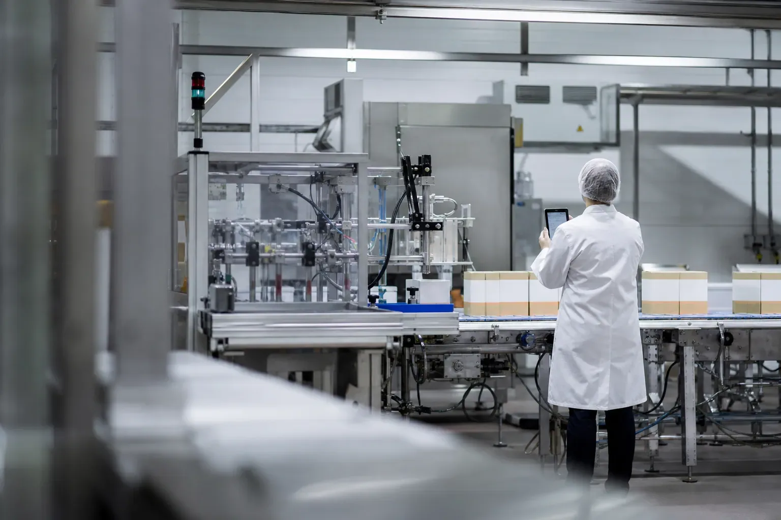 Ligne de conditionnement agroalimentaire avec un opérateur de dos scannant une étiquette depuis une tablette